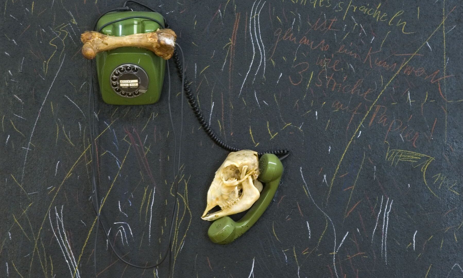 Fluxus Zug, 1982. Telefon, Knochen, Farbstifte, Text auf schwarzer Spanplatte. Dauerleihgabe des Landes Nordrhein-Westfalen.